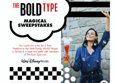 Disney World guest grins, holding a Mickey-shaped treat, celebrating The Bold Type Magical Sweepstakes vacation giveaway.