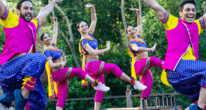 Bollywood dancers in vibrant costumes light up Disney’s Animal Kingdom stage, performing energetically among lush greenery.