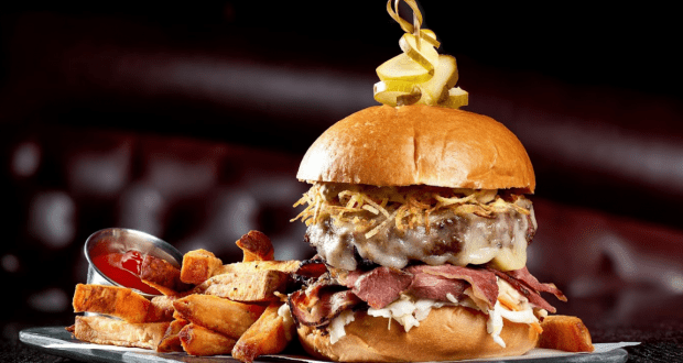 The Edison’s Burger of the Month with roast beef, cheese, crispy onions, coleslaw, and fries served on a metal tray at Disney Springs.