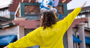 Disney World guest in yellow park shirt and sparkling Mickey ears greets the entrance, ready for an unforgettable weekend adventure.