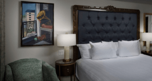 A Riviera Resort hotel room near Disney World, with a plush bed, elegant lamp, cozy armchair, and Disney-inspired framed art.