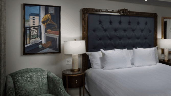 A Riviera Resort hotel room near Disney World, with a plush bed, elegant lamp, cozy armchair, and Disney-inspired framed art.