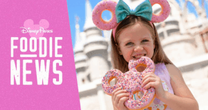 Disney fan with Mickey ear headband enjoys a Mickey-shaped donut at Walt Disney World, beside "Foodie News" April 2019 update.