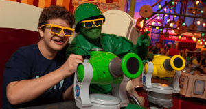 A kid teams up with a Toy Soldier, both in 3D glasses, for an arcade shooting game at Toy Story Land in Walt Disney World.