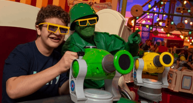 A kid teams up with a Toy Soldier, both in 3D glasses, for an arcade shooting game at Toy Story Land in Walt Disney World.