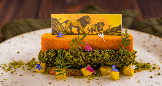 Lion King-inspired dessert at Jiko: edible lion art, green crumbs, yellow cubes, and edible flowers—a Disney dining highlight.