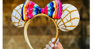 Golden headband with white and gold ears inspired by conchas, topped with a vibrant striped bow, perfect for Disney Parks fans.