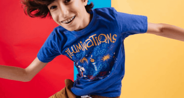 Young Illuminations fan beams in official blue tee against a vibrant red, blue, and yellow backdrop at Walt Disney World.