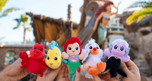 Guests show off The Little Mermaid Wishables plushes in front of an immersive themed backdrop at Walt Disney World.