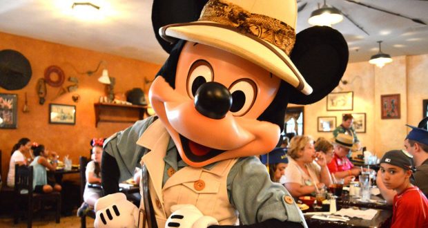 Mickey Mouse in safari gear greets excited guests during character dining at Walt Disney World’s lively restaurant.