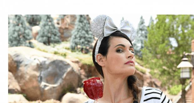 A Disney fan in classic mouse ears savors a red candy apple while enjoying the magical atmosphere of Walt Disney World park.