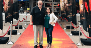 Disney fans celebrate with producer Don Hahn on the red carpet, framed by The Lion King banners at a special event.