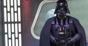 Darth Vader in full black armor and cape stands before a cosmic backdrop at Disney's Hollywood Studios in Walt Disney World.