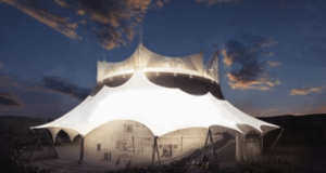 The glowing Cirque du Soleil white tent lights up Disney Springs at night as guests gather beneath a dramatic evening sky.