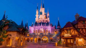 Cinderella Castle aglow at dusk, surrounded by whimsical buildings during Disney After Hours at Walt Disney World.