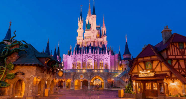 Cinderella Castle aglow at dusk, surrounded by whimsical buildings during Disney After Hours at Walt Disney World.