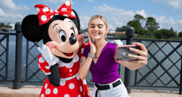 A guest snaps a selfie with Minnie Mouse by the waterfront at Epcot’s International Food & Wine Festival in Disney World.
