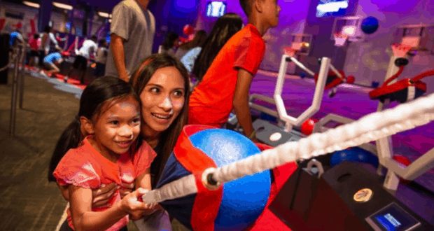 Guests enjoy friendly competition at the NBA Experience, smiling as they shoot hoops together in this bustling, energetic venue.
