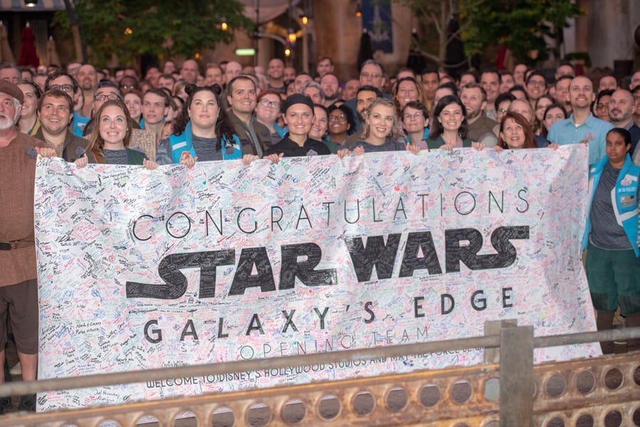 Star Wars: Galaxy’s Edge Opening Team beams for a group photo at Walt Disney World, holding their autograph-covered banner.