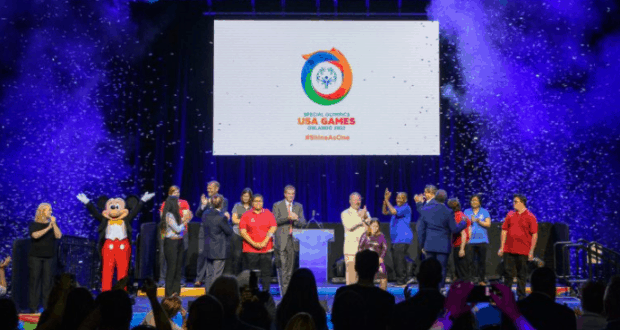 Mickey Mouse joins athletes on stage at Disney World for the 2022 Special Olympics USA Games, with confetti filling the air.