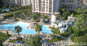 The poolscape at Disney’s Riviera Resort, featuring palm trees, a Tower Slide, and plenty of lounge chairs by the grand hotel.