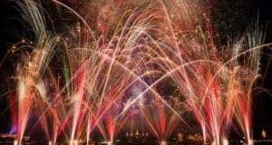 Dazzling fireworks explode over Epcot’s skyline, their colors mirrored on the lagoon, celebrating Epcot Forever at Disney World.