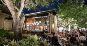 Guests savor Italian cuisine on Terralina’s patio, surrounded by twinkling lights and greenery in Disney Springs’ lively nightlife.