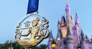 Disney Princess Half Marathon medal displayed with the iconic Cinderella Castle at Walt Disney World in the background.