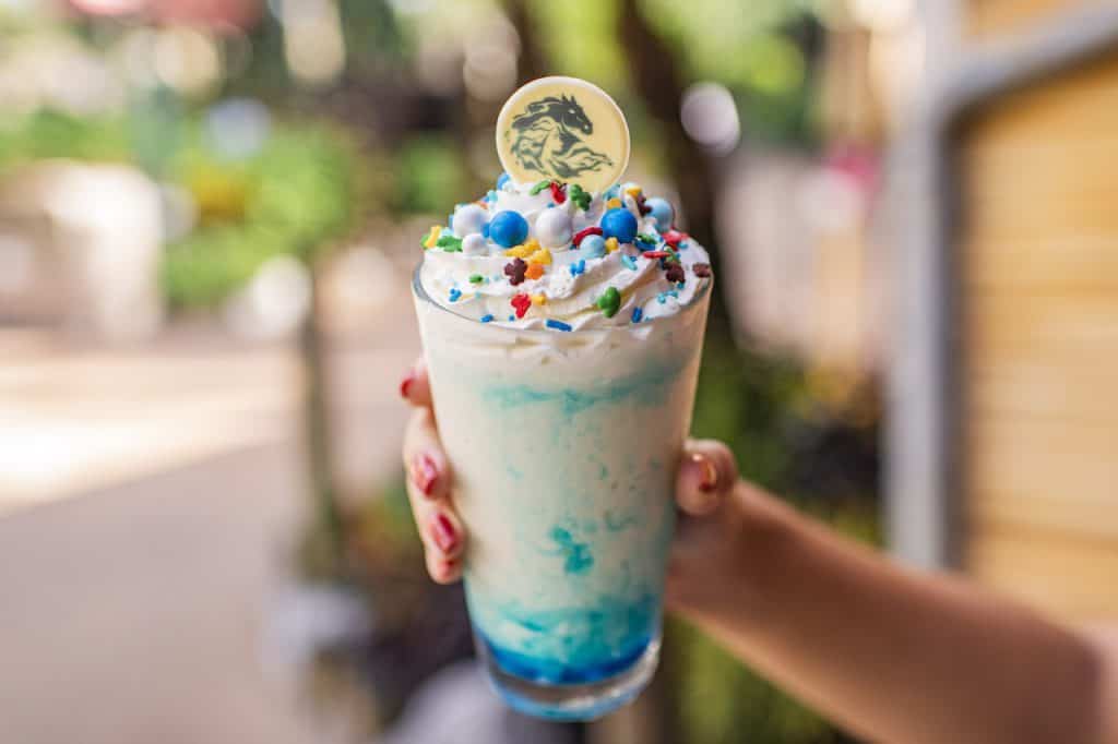 Sip on the magic with this blue and white milkshake, topped with whipped cream, sprinkles, and a dino chocolate from Disney World!.