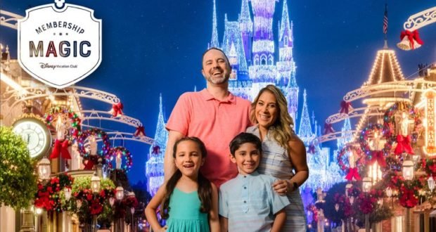 A happy family beams in front of Cinderella Castle aglow with holiday lights and festive backdrops at Walt Disney World.