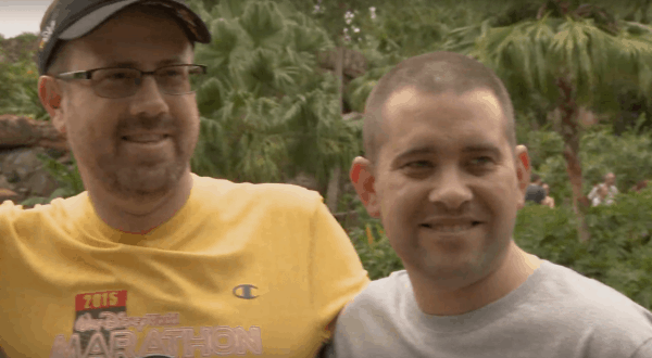 Two happy runners celebrate their Disney Wine & Dine Half Marathon finish, surrounded by magical greenery in the park.
