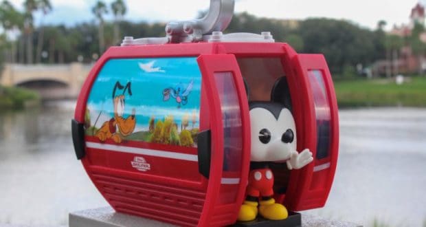 Mickey Mouse Funko Pop waves from a vibrant red Disney Skyliner gondola, decked out with playful Disney character art.