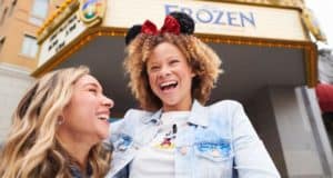 Fans in Mickey ears beam outside a "Frozen 2" theater, enjoying enchanting photo ops at Walt Disney World.