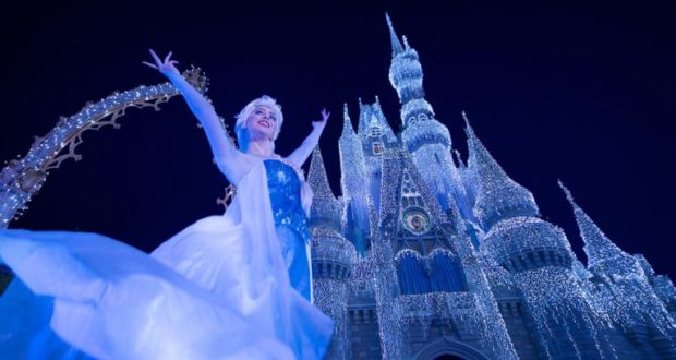 Elsa beams in front of the dazzlingly lit Cinderella Castle during Frozen Holiday Wish at Walt Disney World.