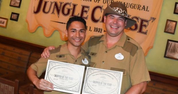 Jungle Cruise Skippers celebrate their Skipper of the Year win at Walt Disney World, posing with certificates by the attraction banner.