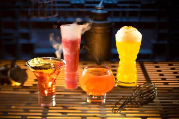 Four vibrant specialty cocktails with dramatic smoke and foam effects light up the bar at Hollywood Studios, ready for your cheers.