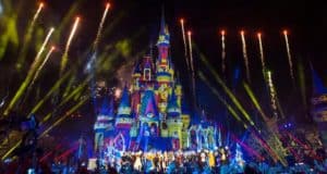 Brilliant fireworks burst over Cinderella Castle, illuminating a festive crowd during Disney’s Magical Holiday Celebration.