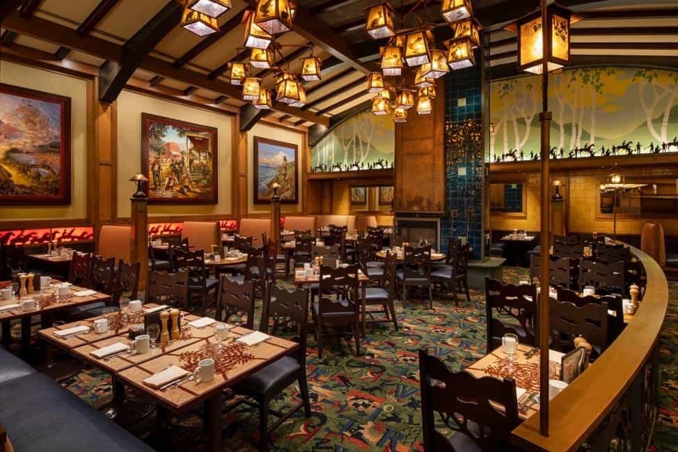A warmly lit, wood-beamed restaurant with forest décor and vibrant carpet, serving Disney Parks Best Bites in a magical setting.