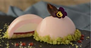 Decadent pink mousse dessert with chocolate leaf and edible flower, sliced to reveal creamy layers—a star at Epcot’s 2020 Arts Fest.