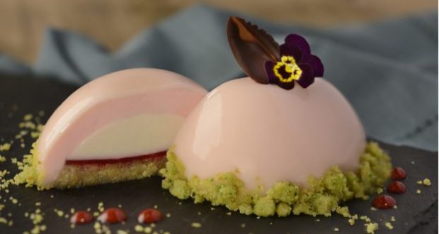 Decadent pink mousse dessert with chocolate leaf and edible flower, sliced to reveal creamy layers—a star at Epcot’s 2020 Arts Fest.