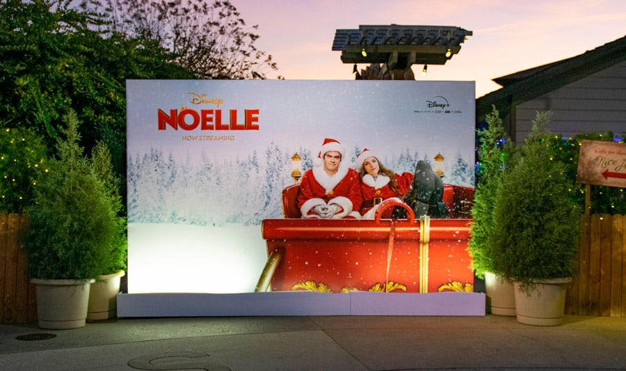 Noelle movie poster with Anna Kendrick and Bill Hader in a red sleigh, Christmas décor evoking Disney Springs holiday magic.
