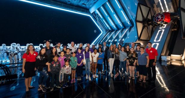 Fans gather in a Star Wars-themed Disney World room, with stormtroopers and a TIE fighter setting the scene for family fun.