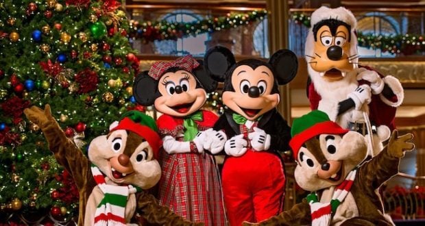 Mickey, Minnie, Goofy, Donald, and Pluto in Christmas costumes gather by a twinkling tree aboard Disney Cruise Line.