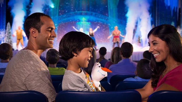 Guests delight in a Disney World stage show as their child clutches an Olaf plush, celebrating with Florida Resident Discover Disney Tickets.