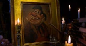 Framed cartoon portrait of a smiling man glows by candlelight, evoking the playful vibe of Epcot’s Festival of the Arts.