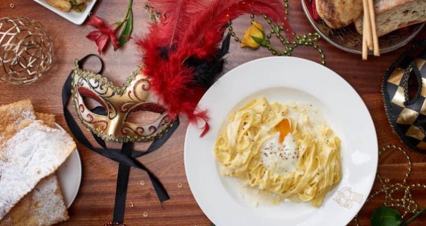 Pasta with a poached egg, red feathered mask, and festive decor set the stage for Carnevale at Epcot’s Italy Pavilion.