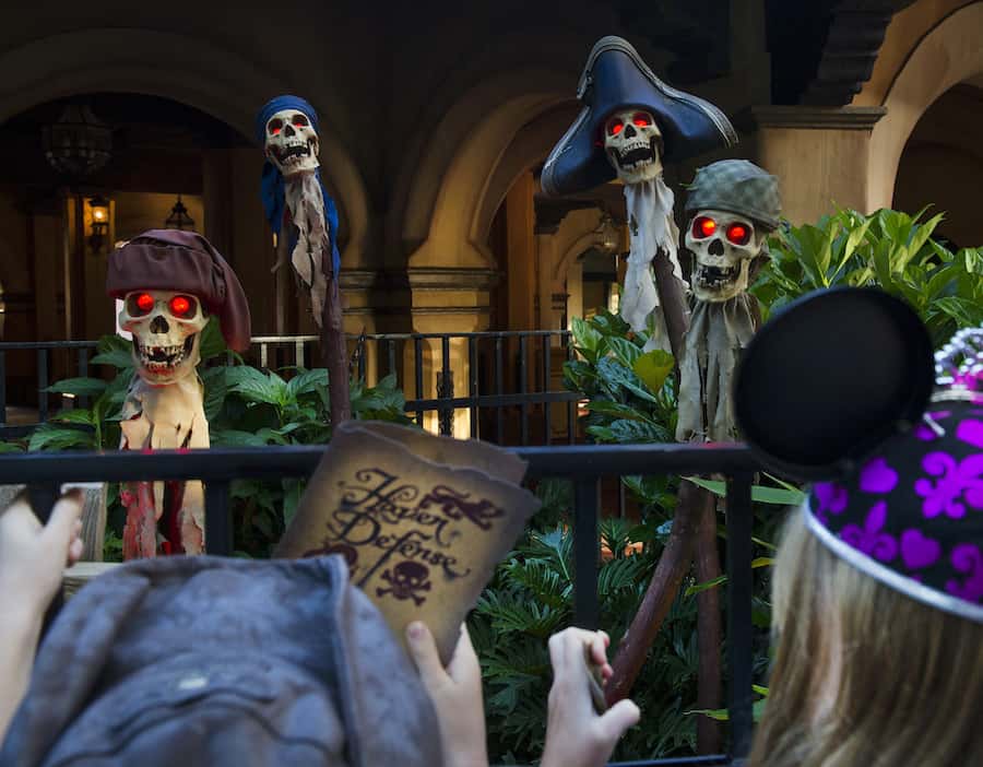 Pirate skeletons with glowing red eyes greet a Disney fan in Mickey ears, map in hand, imagining their own pirate adventure.