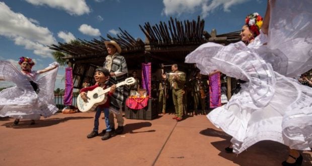 Mariachi Cobre brings Coco’s story to life at EPCOT, performing in vibrant Mexican attire under the sunny festival sky.