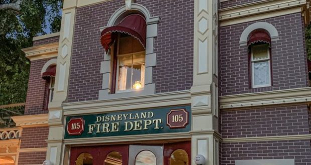 Disneyland Fire Dept. station with classic brick facade and red awnings, warmly lit to greet park guests on Main Street, U.S.A.