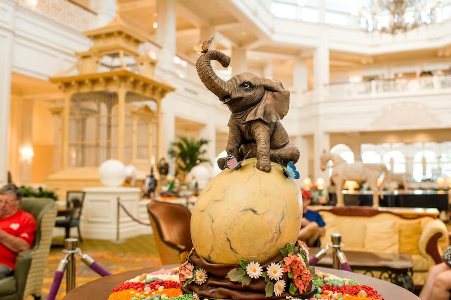 A lifelike elephant sculpture crowns a festive, candy-adorned Easter egg display at Walt Disney World.